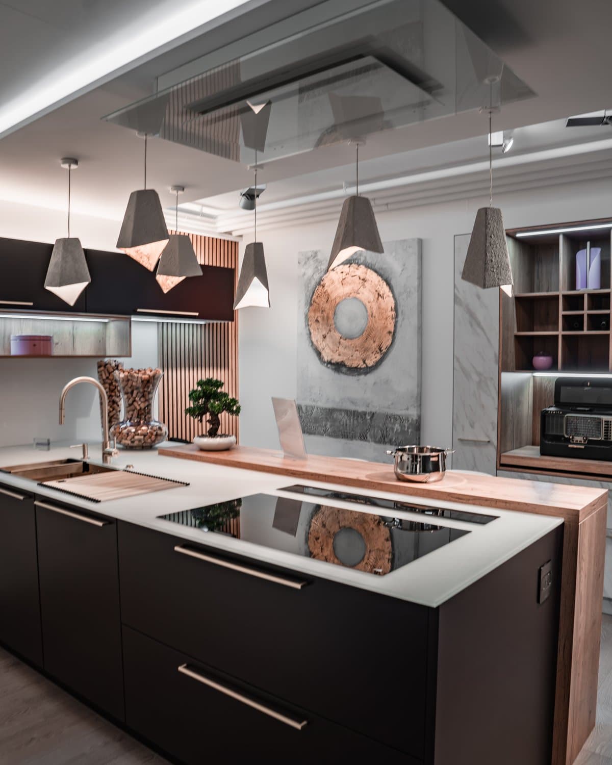 Îlot noir avec plan de cuisson, suspensions en béton et rangements bois